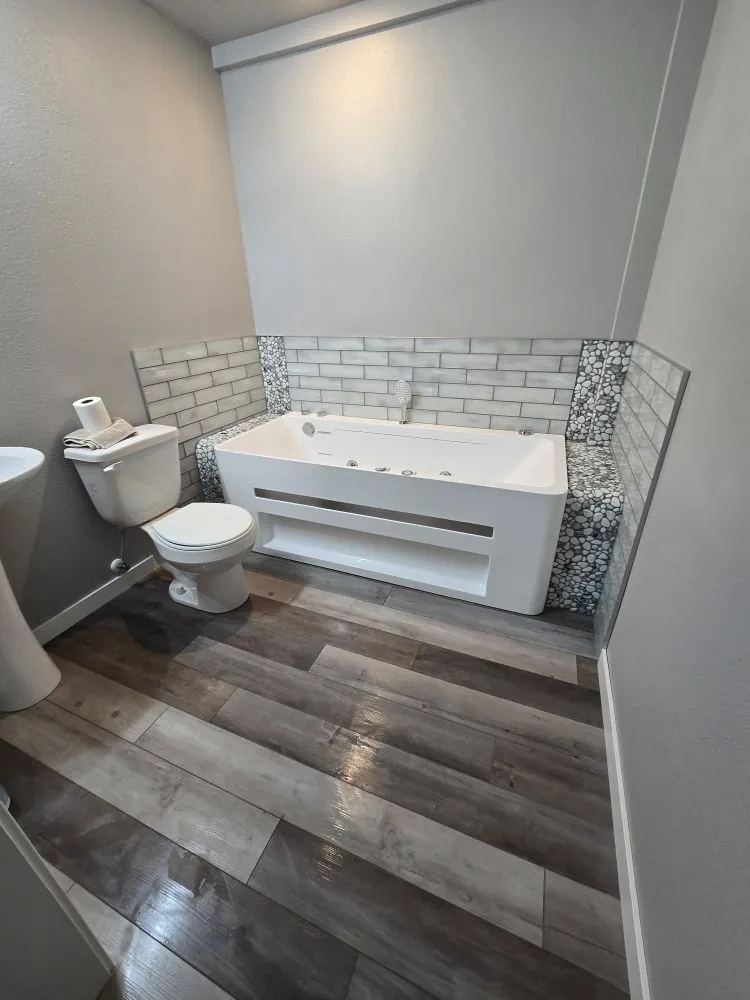 Custom jacuzzi tub surround with subway tile, pebble accent, and waterproof LVP flooring.